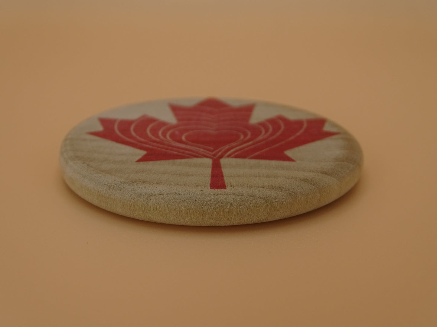 "Compassion Compass" Canadian Edition-Smooth wooden disc with a red maple leaf design on Maple Wood